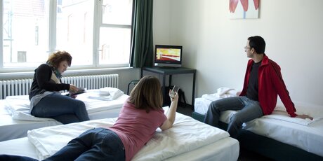 drei Gäste auf Betten in Hostelzimmer